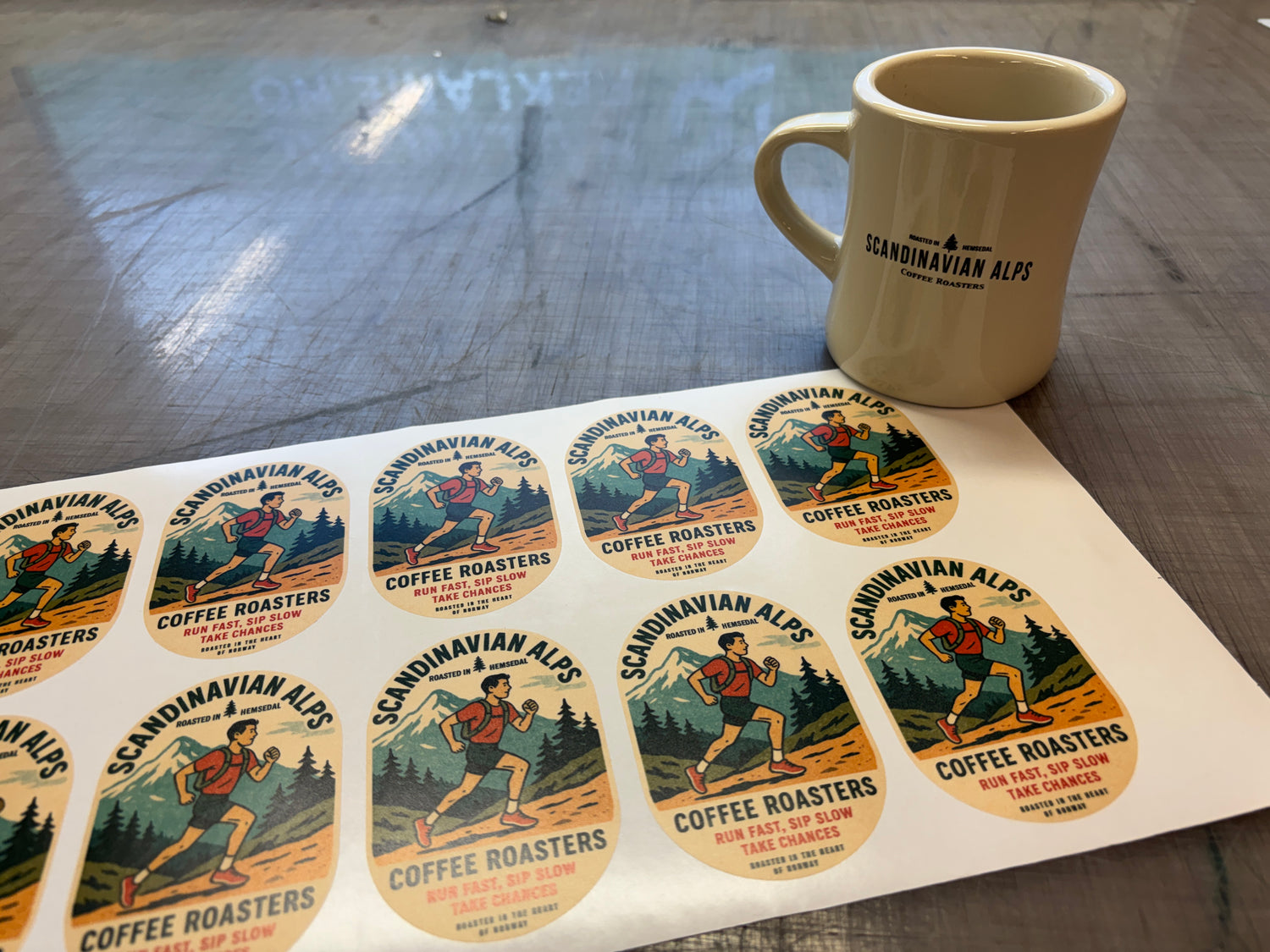 Scandinavian Alps Coffee Roasters stickers on a sheet with a mug in the background.